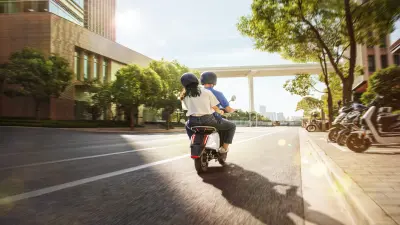 Woman riding at the back of a scooter with a professional driver.